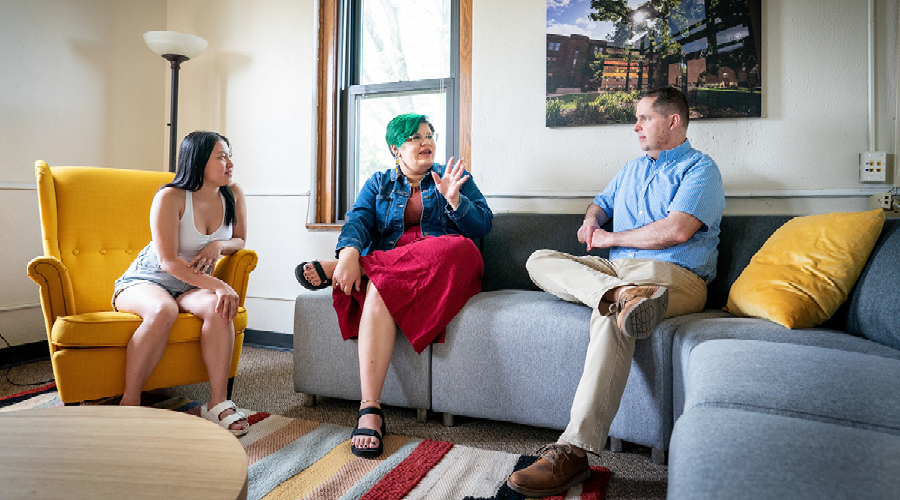 Tim Pippert (right) talks with Augsburg Family Scholars students, Madelyne Yang ’26 (left) and Donovan Holmes ’26 (middle) in the Augsburg Family Scholars lounge on campus.